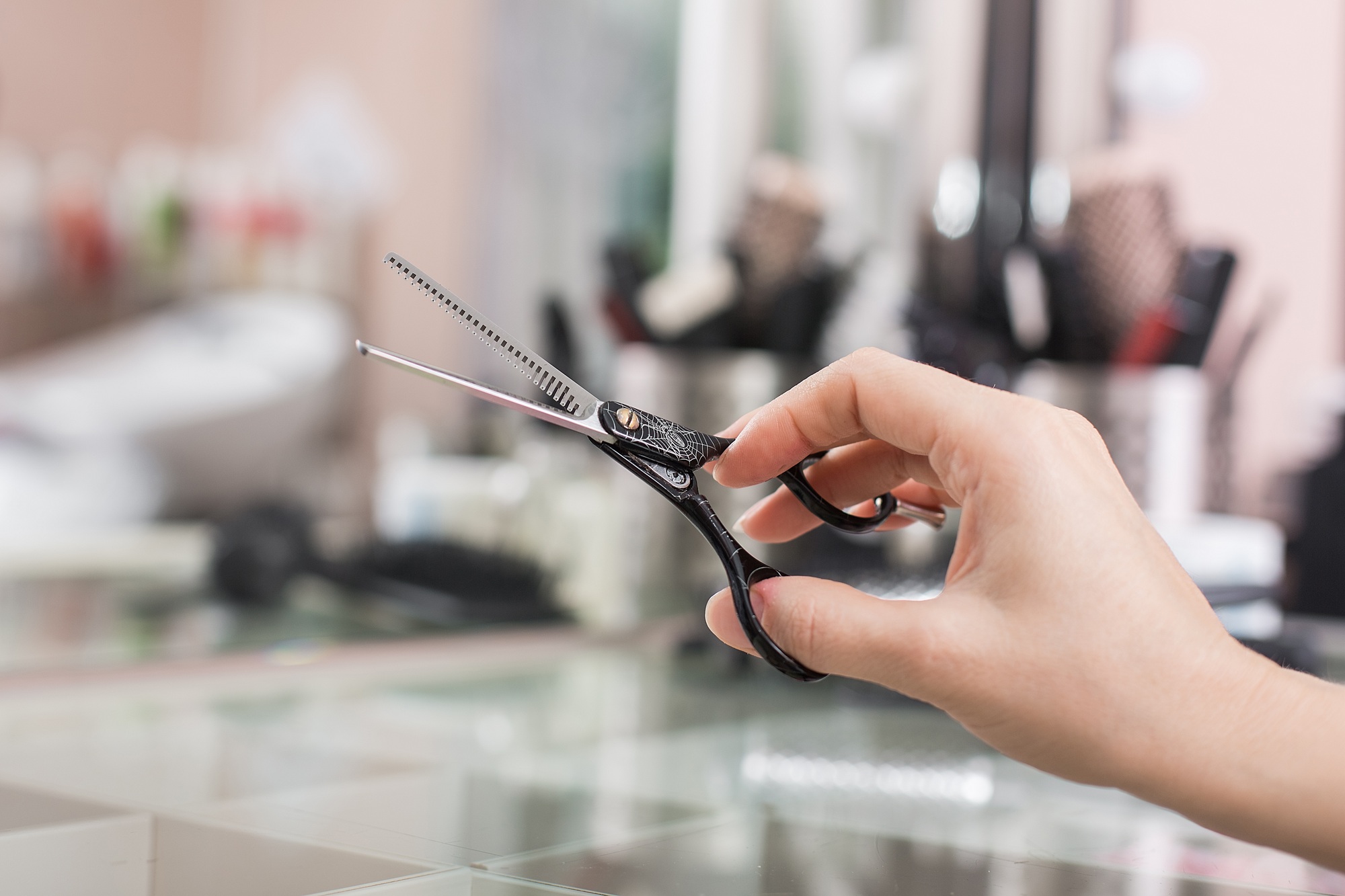 The master hairdresser holds scissors in his hand. Close-up on the background of the workplace